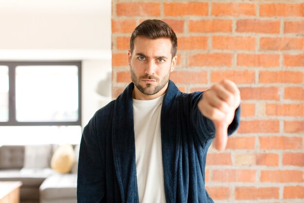 Foto uomo che si sente arrabbiato, arrabbiato, infastidito, deluso o scontento, mostrando i pollici verso il basso con uno sguardo serio