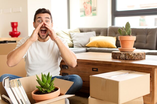 man feeling  happy, excited and positive, giving a big shout out with hands next to mouth, calling out