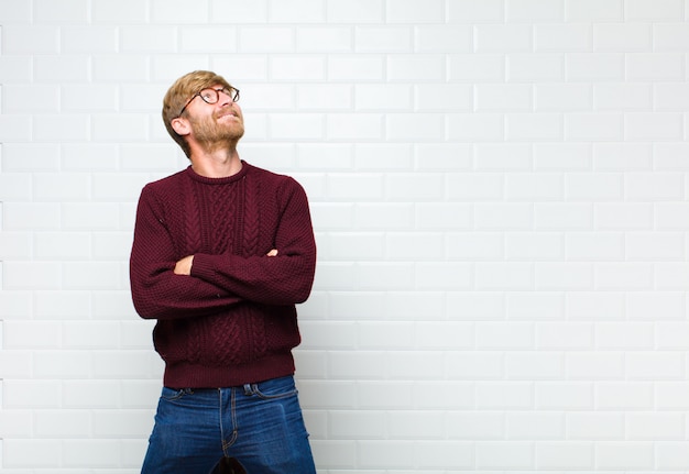 Man feeling happy, proud and hopeful, wondering or thinking, looking up to copy space with crossed arms