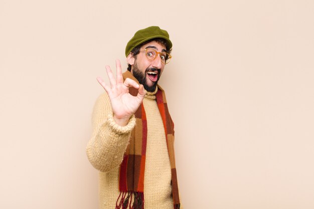 Man feeling successful and satisfied, smiling with mouth wide open, making okay sign with hand