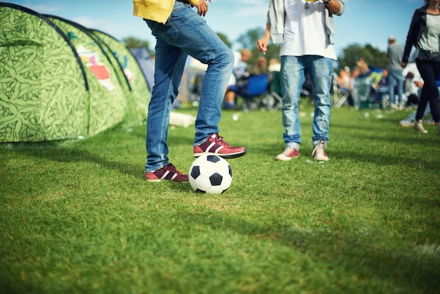 Foto uomo piedi e giocare con la palla da calcio fuori della sua tenda gruppo di colorato campeggio fila di tende posizionate a terra a concerto musicale evento di intrattenimento e celebrazione di carnevale festa sportiva