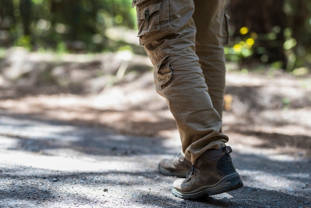 Man feet wearing hiking shoes walking through the forest path in summer, man walking through footpath. Low section of men hiking in shoes on rough footpath