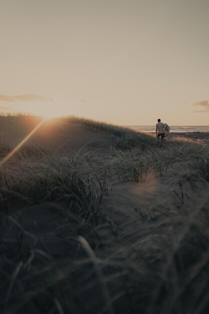 Man on field against sky during sunset