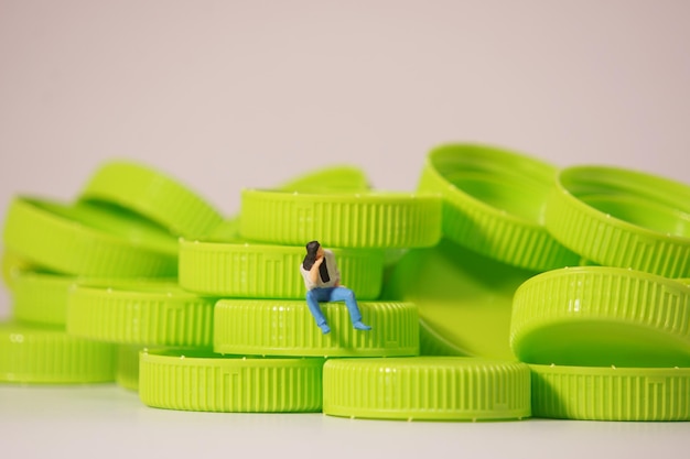 Man figure siting on plastic cap recycle material concept