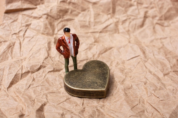 Man figurine standing beside metal Heart for love concept