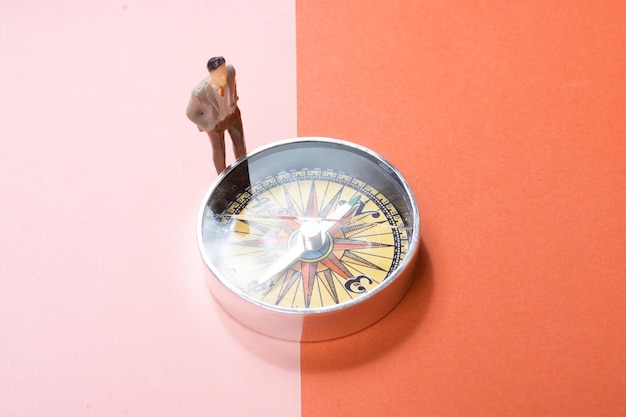 Man figurine standing on Compass as a concept of traveling