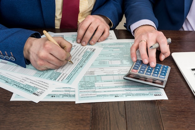 Uomo fillilng e contabilità finanziaria documento fiscale modulo 1040 con calcualtor. tempo per le tasse