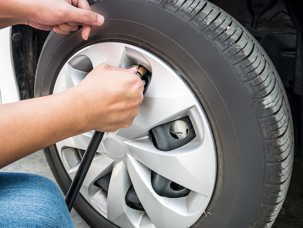 Uomo che riempie la pressione dell'aria nel pneumatico dell'auto si chiuda