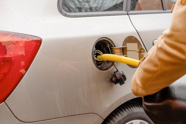 Photo a man filling fuel tank of his car with diesel fuel off the jerry can as there is no fuel