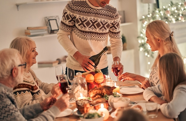 The man fills wine glasses above the festive table