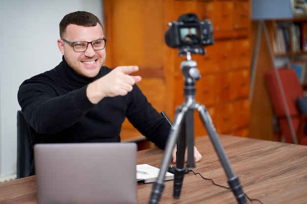 Man filming video blog on camera with tripod for online followers. In social media, Influencer, new technology and internet concept