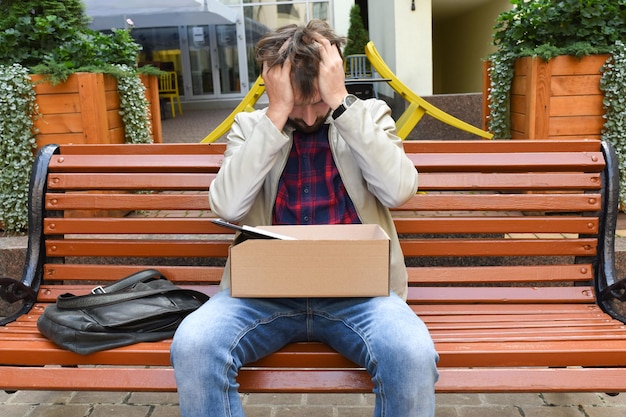 A man fired from his job in despair sits on a bench 