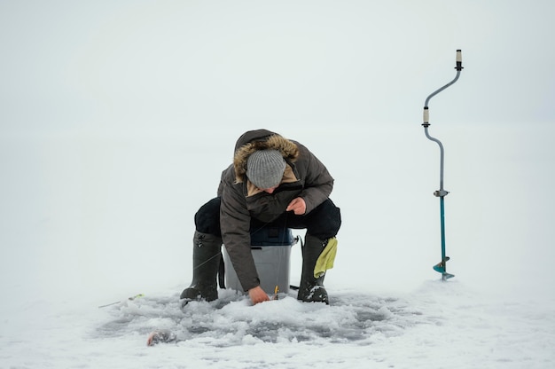 Фото Мужчина ловит рыбу в одиночестве на улице зимой