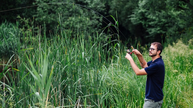 Photo man fishing on lake with grown grass weed