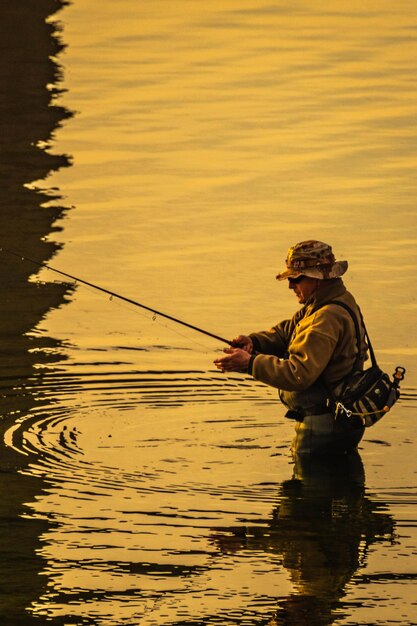Мужчина ловит рыбу в озере.