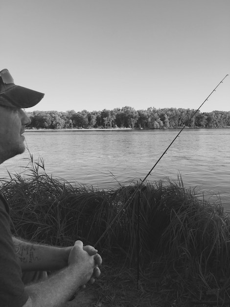 Man fishing at lakeshore against clear sky