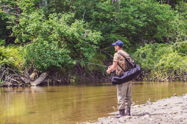 Man fishing on a mountain river with a ultralight spinning using fishing wobblers. He got his hook hooked for something.