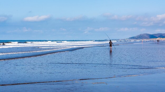 Man fishing in sea against sky