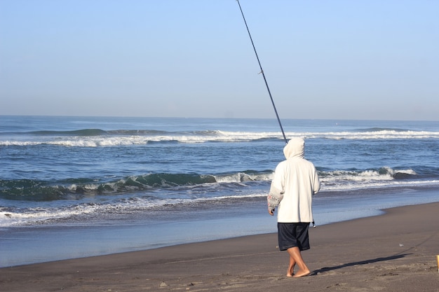 Uomo che pesca in mare dalla spiaggia