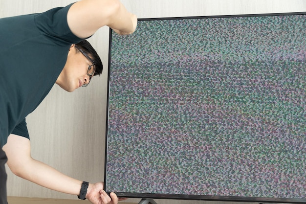 A man fix television lost signal noise on screen looking cable behide