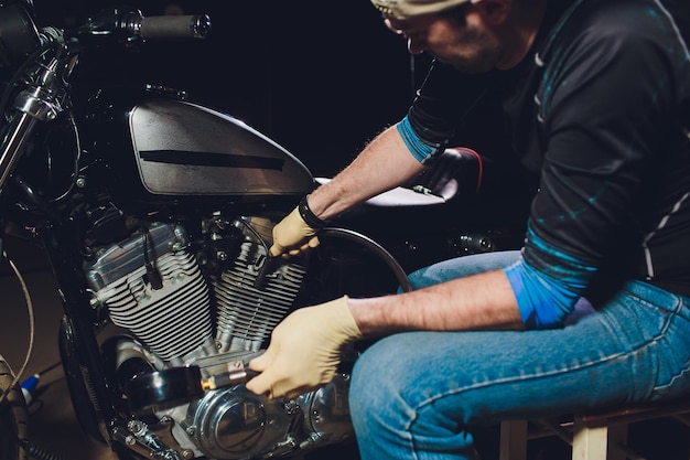 Foto uomo che ripara la bicicletta giovane sicuro di se che ripara una moto vicino al barometro del suo garage