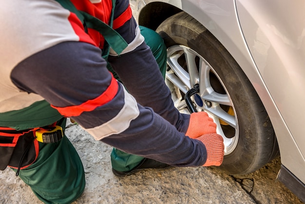 Man fixing car wheel with spanner close up