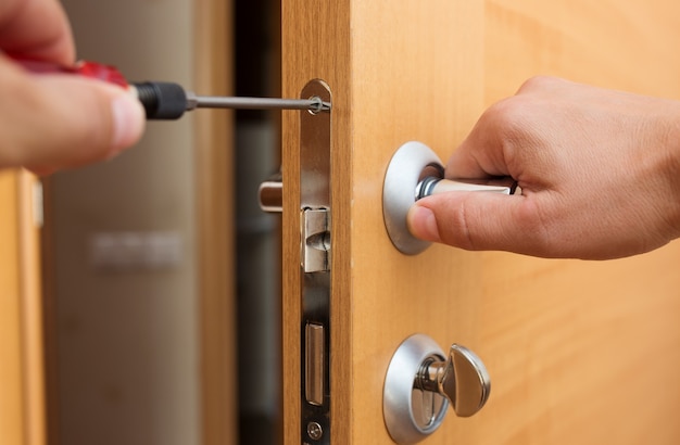 Man fixing the door handle with screwdriver