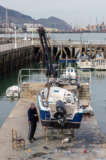 Man fixing fishing boat in port in town