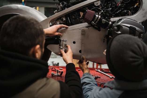 Photo man fixing a motorcycle in a modern workshop