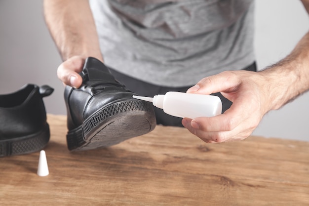 Man fixing shoe with a glue.