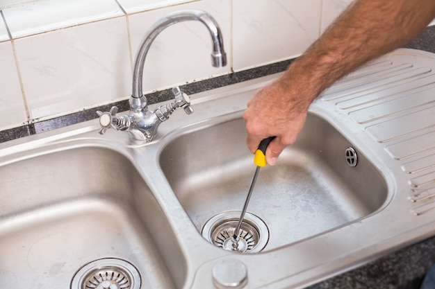 Man fixing sink with screwdriver