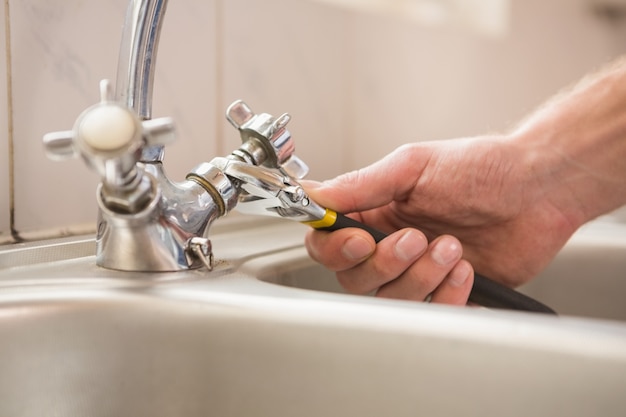 Man fixing tap with pliers