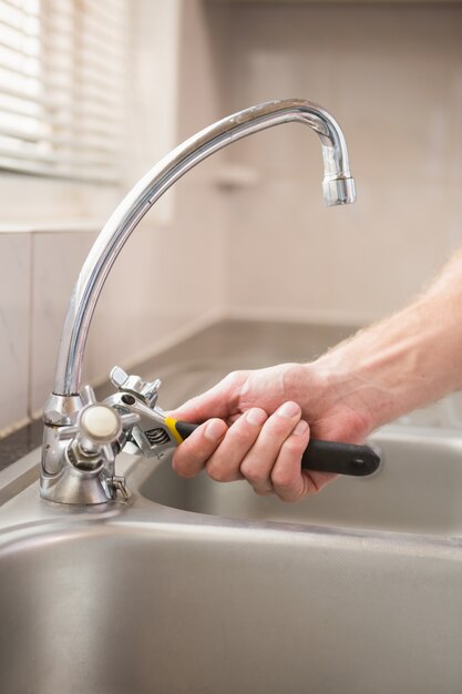 Man fixing tap with pliers