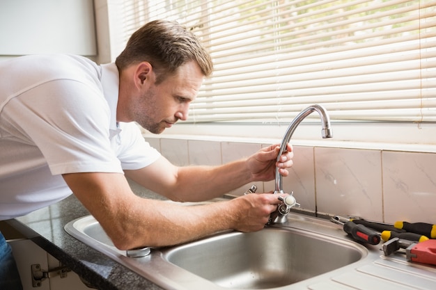 Man fixing tap with pliers