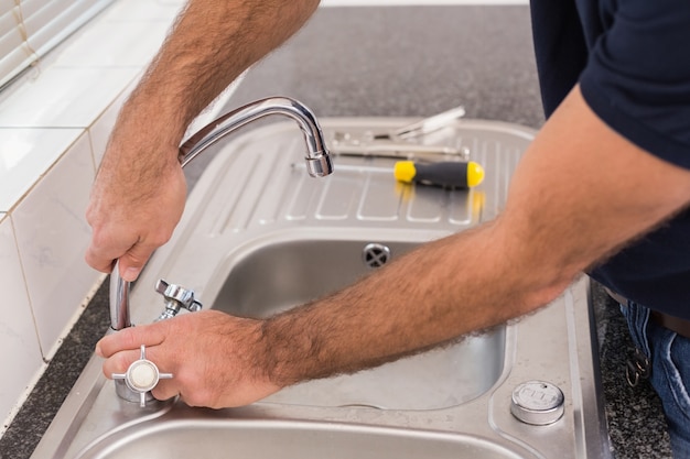 Man fixing tap with pliers