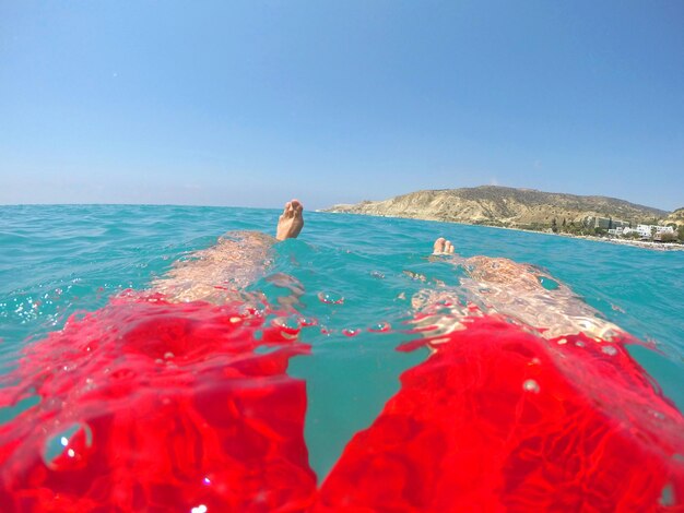 Man floating on sea water feet and legs of a swimmer in red swimwear floating in the sea