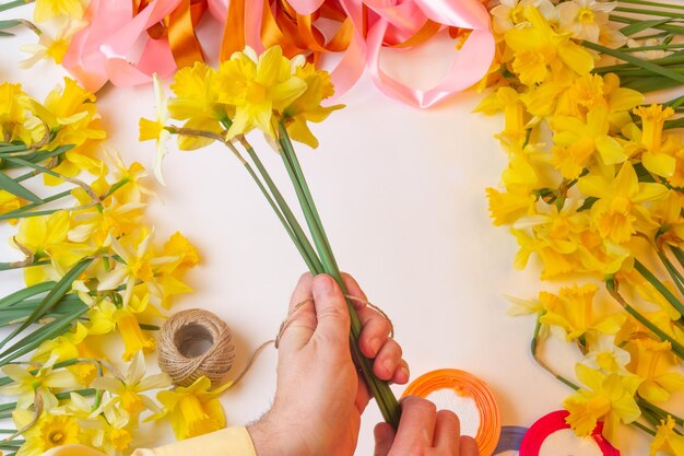 Man florist makes bouquets of flowers daffodils