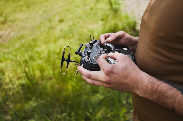 Foto uomo che pilota un drone da corsa ad alta velocità con drone quadricottero aereo remoto con telecomando