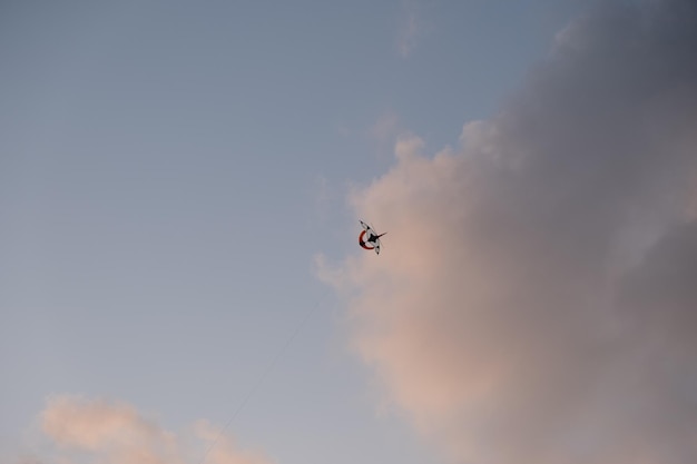 A man flying a kite with a red and white stripe on it.