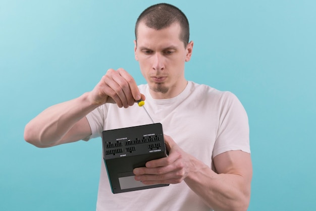 A man focused on the repair of a computer power supply with a
screwdriver on a blue background hand workers electronic supply
component connection fixing repairman unit