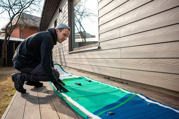 Man folding an inflatable standup paddleboard SUP on a wooden deck next to a modern home