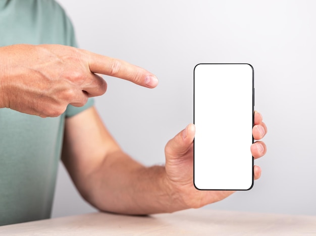 Indice dell'uomo che punta al telefono mockup in posizione verticale uomo che mostra o consiglia il sito web di informazioni sull'applicazione sullo smartphone