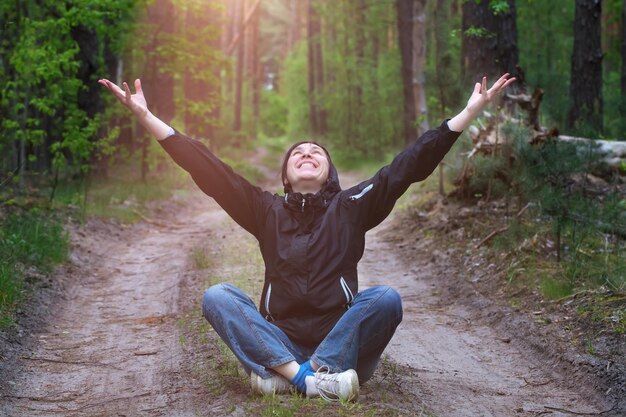 Man in the forest A middleaged woman sits on a forest road lit by the sun