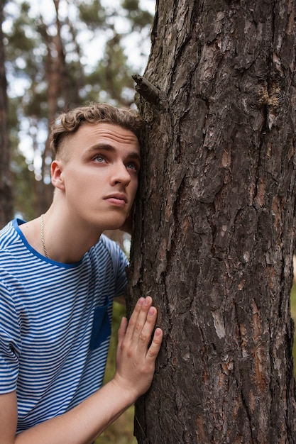 man in forest. young dreamy guy among the trees