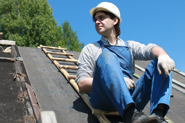 Photo a man in the form of a builder repairs a house