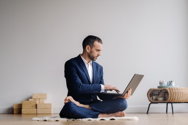 A man in a formal suit works sitting in a fitness room on a laptop