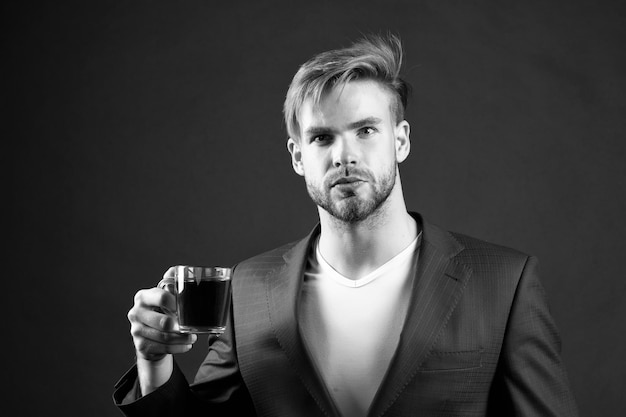 Man formeel elegant pak geniet van koffie donkere achtergrond Zakenman elegante kerel drinkt thee of koffie 's ochtends koffie concept Pauze om te ontspannen en op te laden energie cafeïne drank Heb een kopje koffie