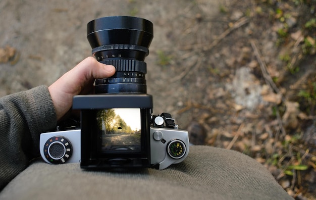 Man fotograaf maakt landschapsfotografie met oude filmcamera in de lente of zomer toerisme en wandelconcept bovenaanzicht kopieerruimte