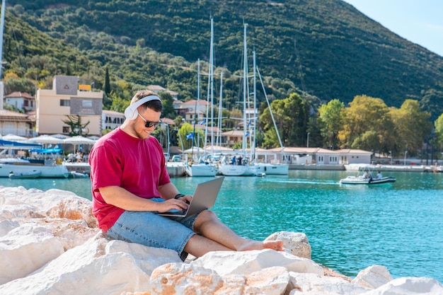 Man freelancer aan het werk op laptop bij stadshavenbank zomertijd