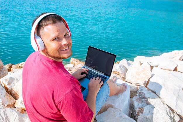 Man freelancer working on laptop at city harbor bench summertime